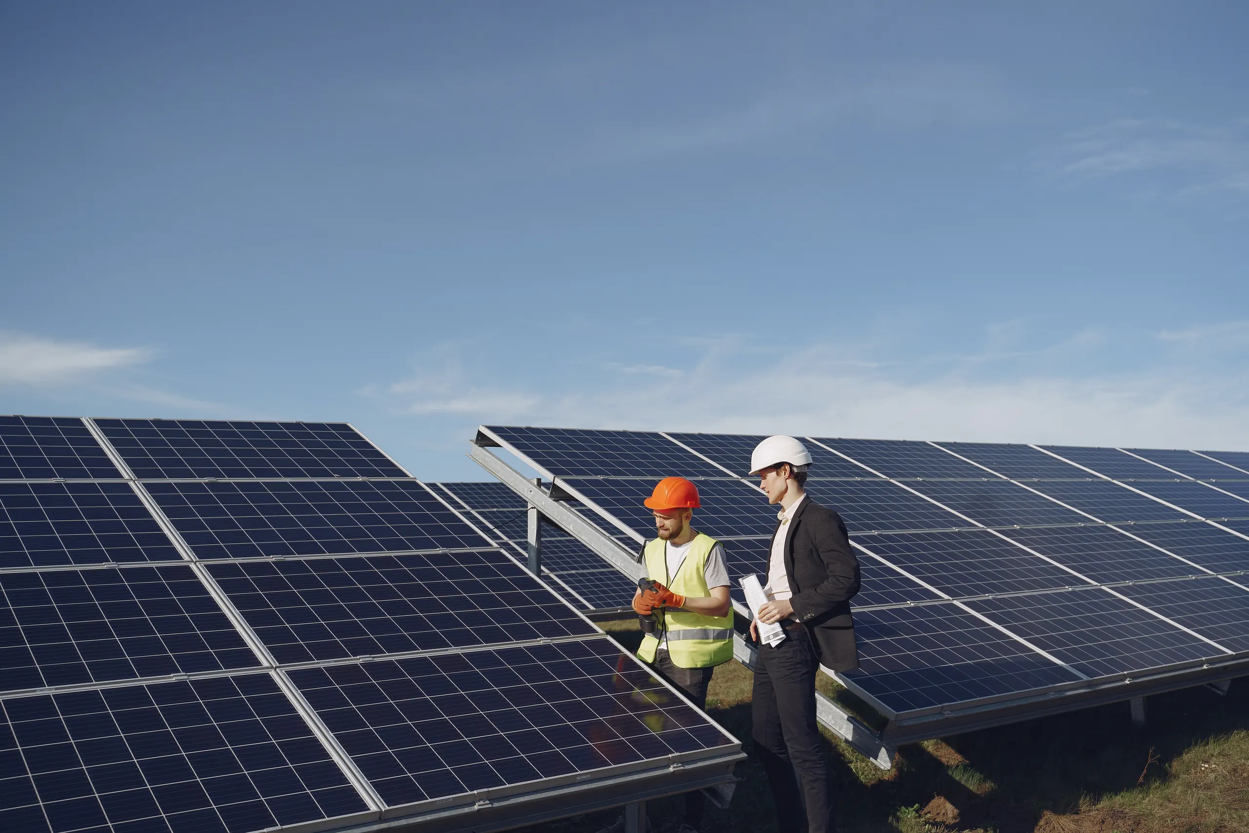 A solar engineer and a client in hard hats reviewing a solar installation